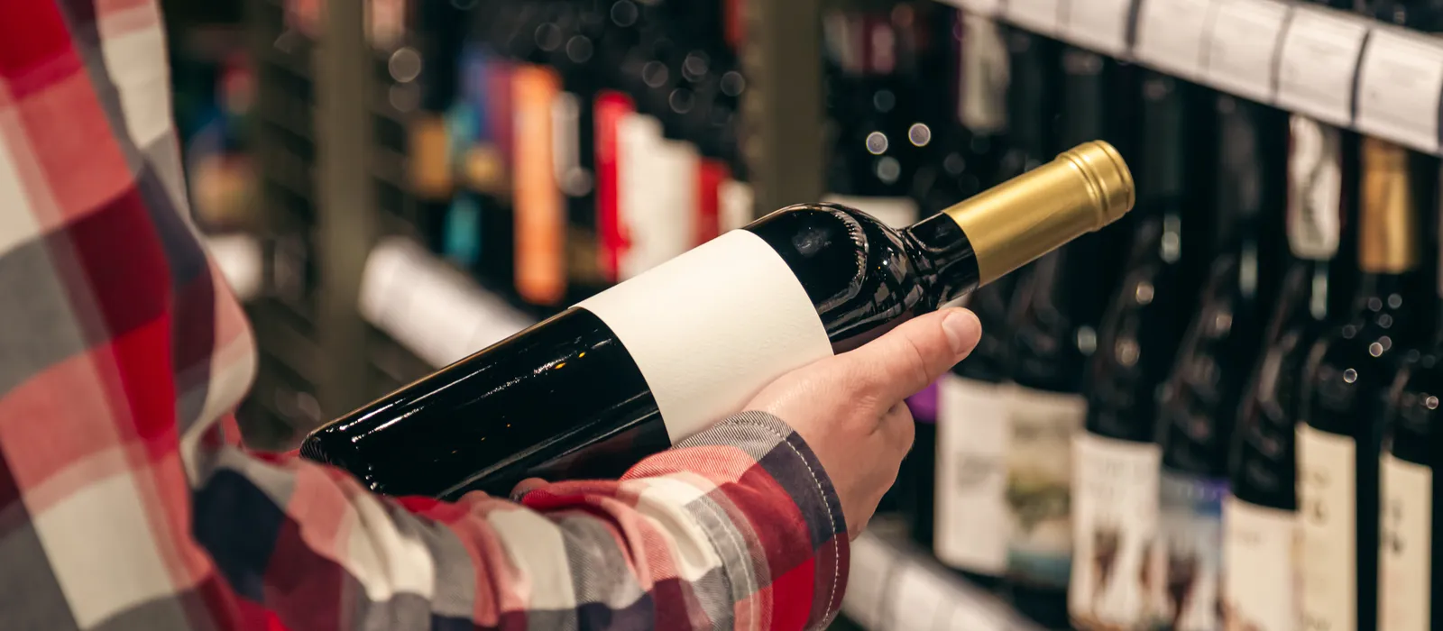 1761235907-male-customer-holding-bottle-red-wine-close-up