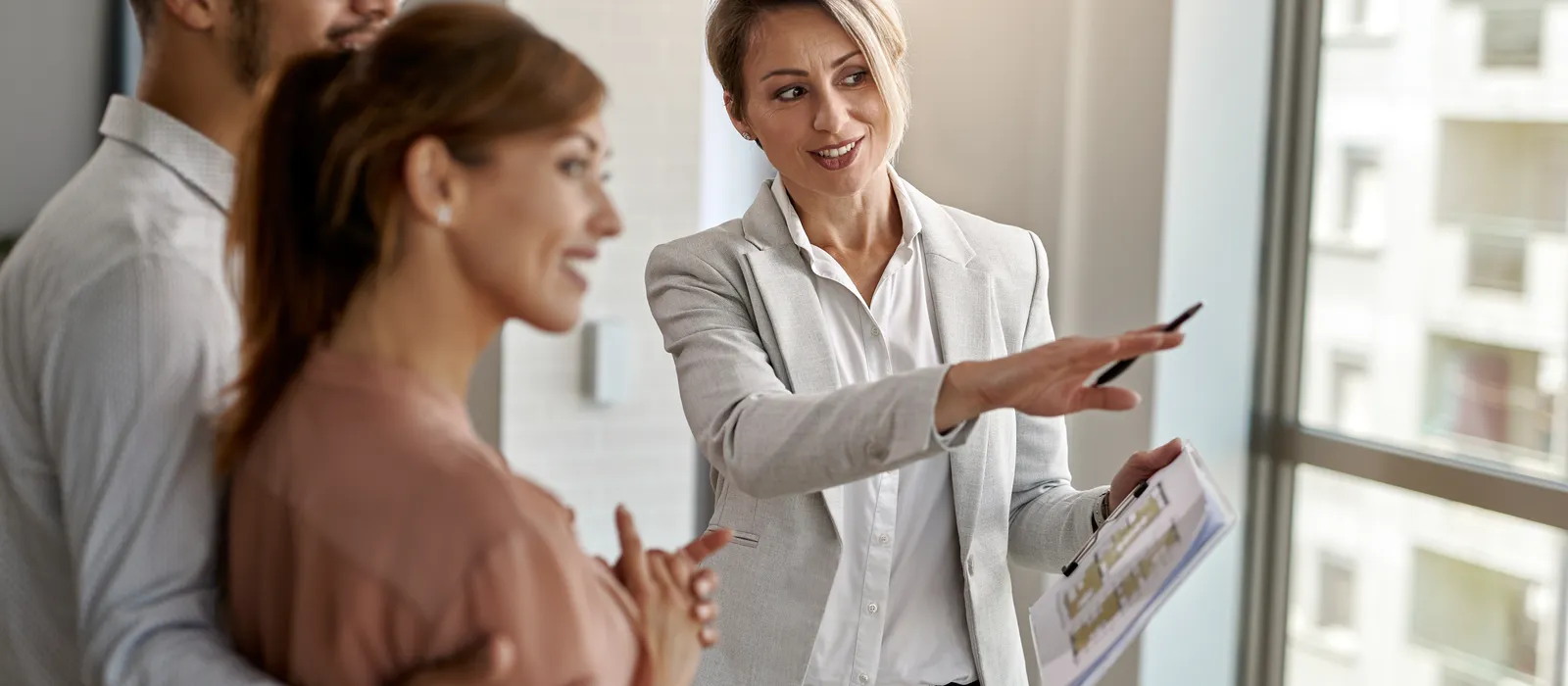 1768481722-smiling-real-estate-agent-talking-with-couple-interested-buying-new-home