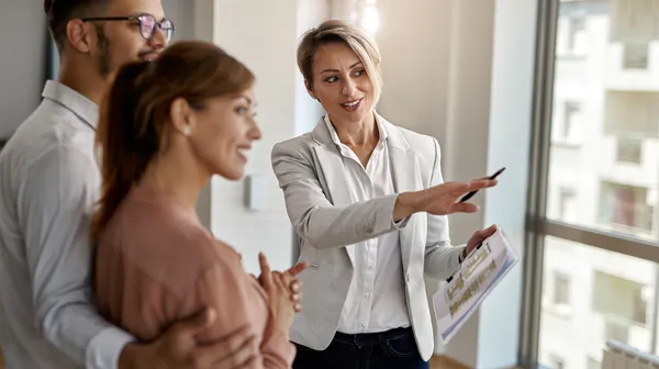 1768481722-smiling-real-estate-agent-talking-with-couple-interested-buying-new-home