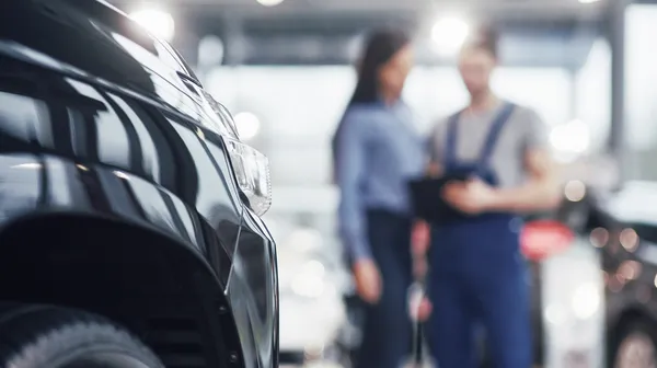 1769088398-beautiful-young-woman-is-talking-handsome-car-mechanic-while-repair-car-dealership