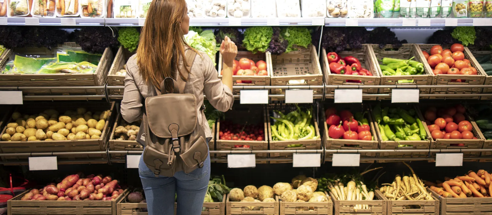 Good looking woman standing front vegetable shelves choosing what buy