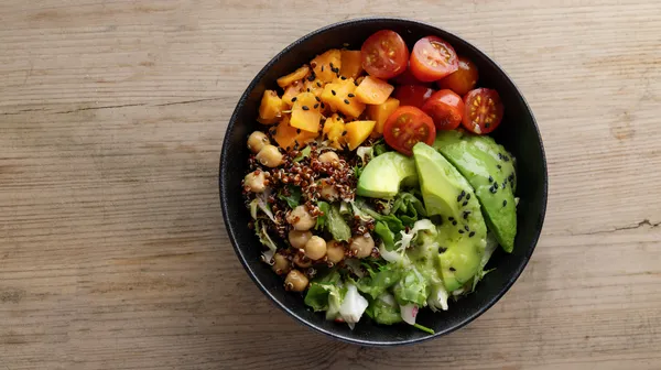 Tasty fresh poke bowl with avocado quinoa vegetables top view