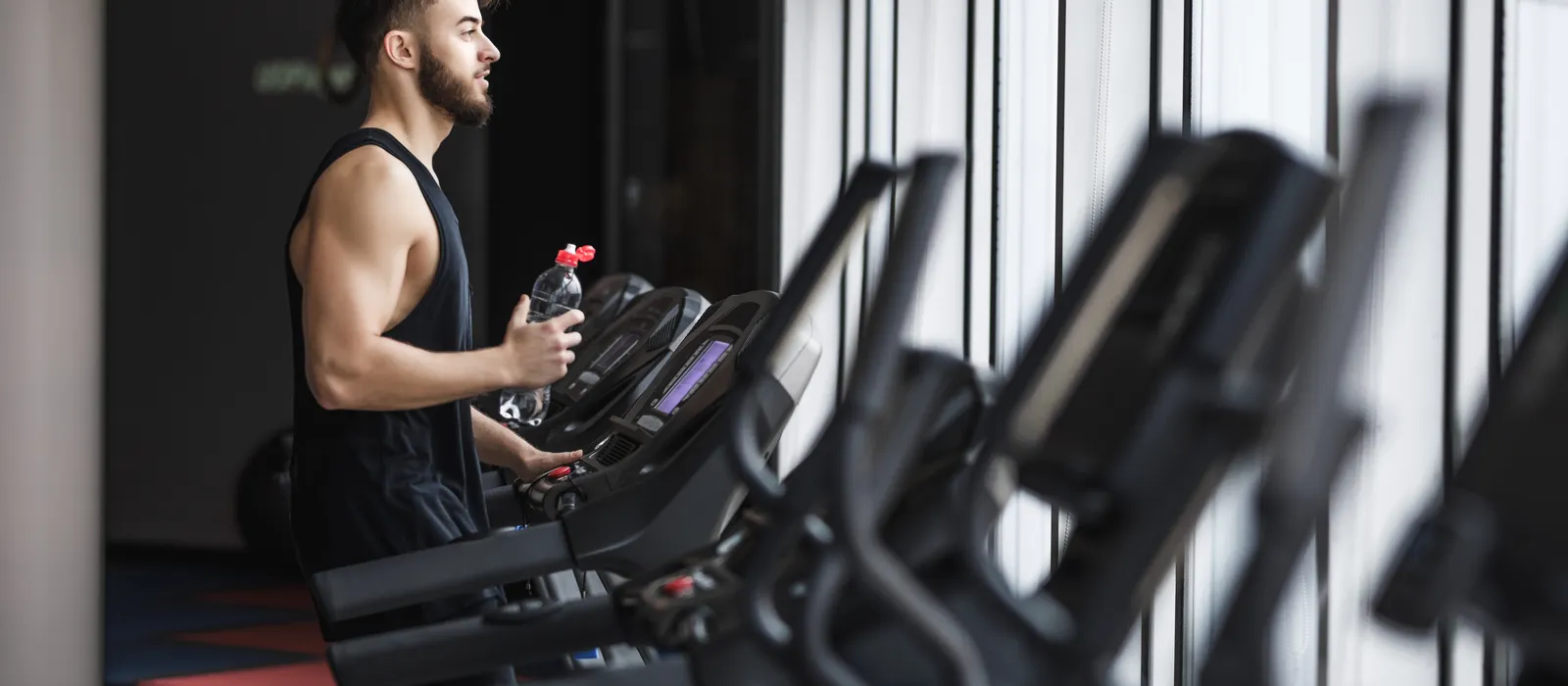 Portrait young sportsman making cardio workout drinking water gym