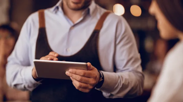 Closeup waiter taking order touchpad while talking guest pub