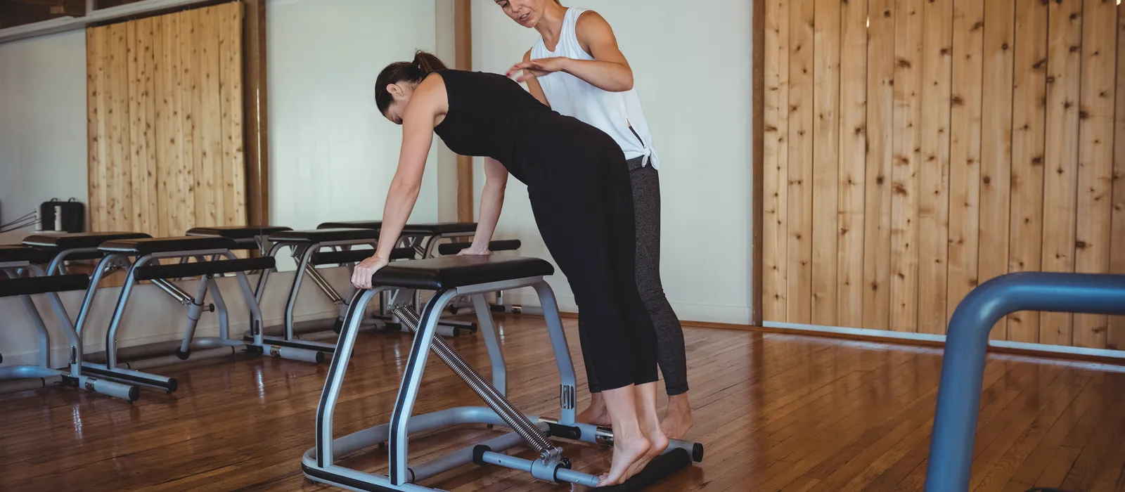 Trainer helping woman while practicing pilates