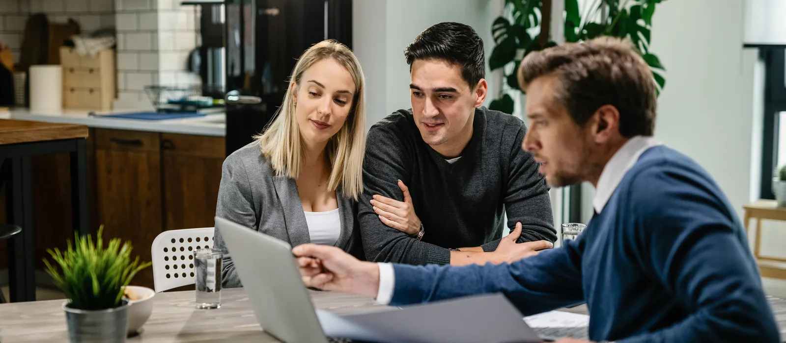 Young couple real estate agent using laptop while going through housing plan meeting